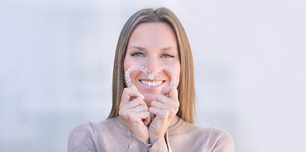 Girl holding invsalign in her hands and smiling