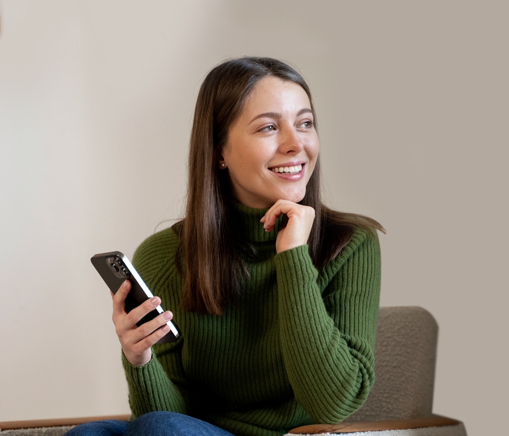 Woman in green sweater using smartphone.
