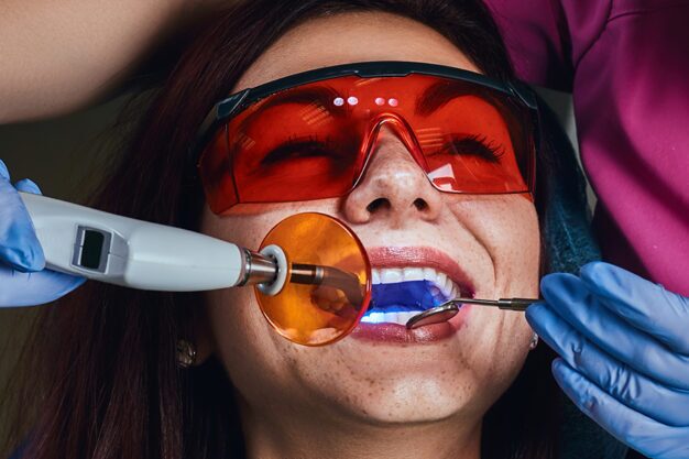 Female patient receiving low-level laser teeth whitening treatment.