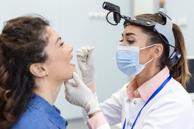 Dentist with headlamp examining patient’s teeth.