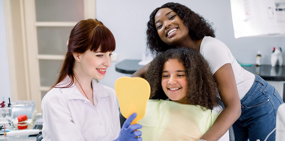 dentist showing mirror to kid and kid is smiling