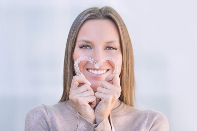 Girl holding invsalign in her hands and smiling