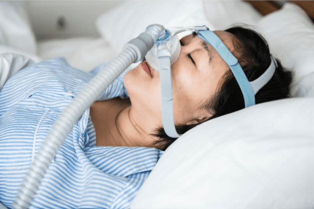 Lady is sleeping with cpac device on her nose
